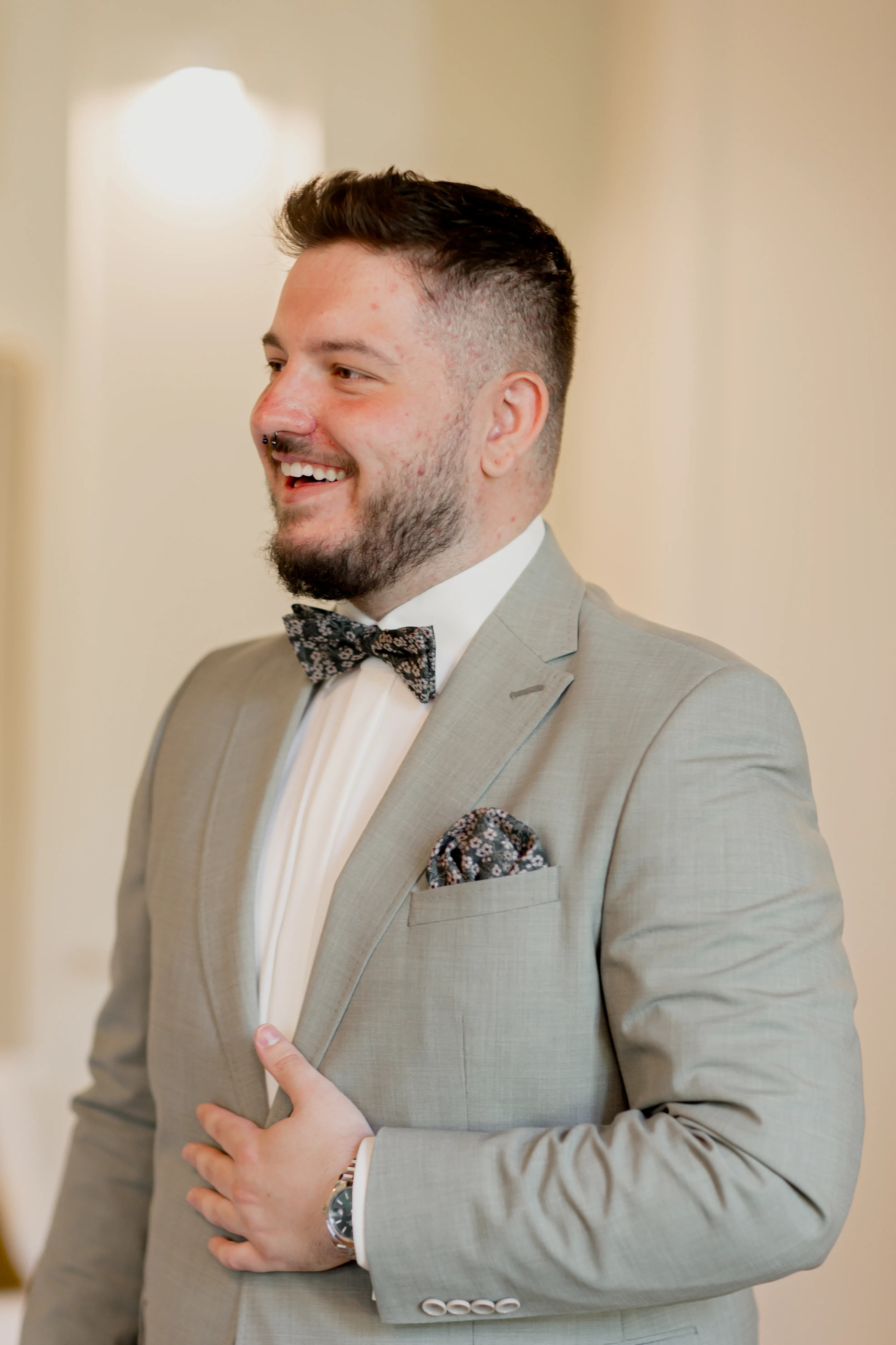 Marcel Reinhart, Gründer von Ein Bein Digital, steht lächelnd in einem hellen Innenraum und trägt einen eleganten hellgrünen Anzug mit weißem Hemd, gemusterter Fliege und passendem Einstecktuch.